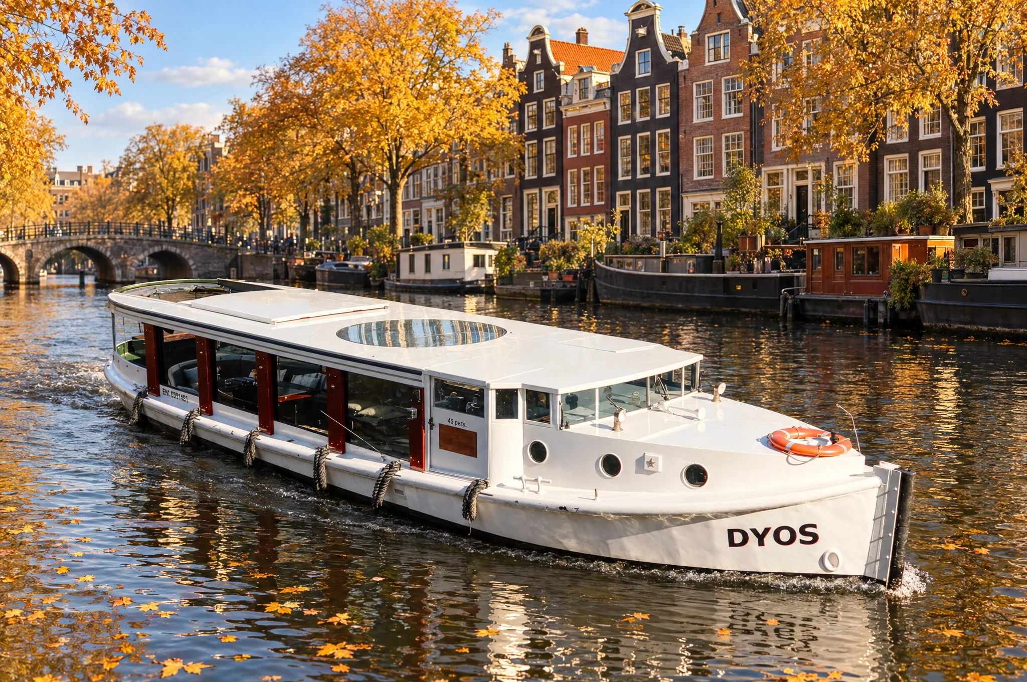 The Dyos, a white saloon boat with an oval glass roof, on an Amsterdam canal in autumn.